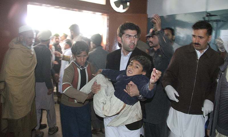A man transfer a injured minor to a hospital in Swat. Photo taken from Dawn 